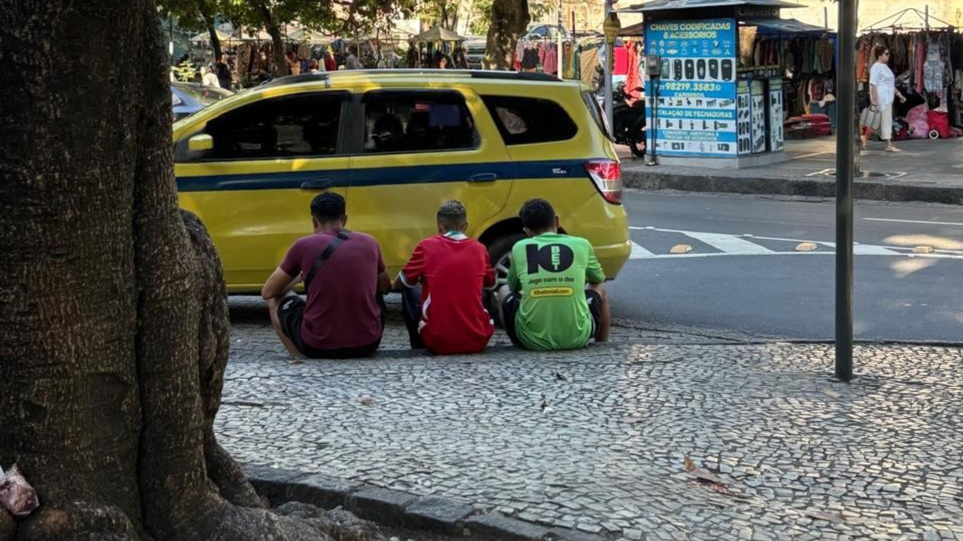 Entregadores no ponto de espera do Largo do Machado se reúnem de acordo com suas afinidades enquanto esperam as corridas. Largo do Machado, Rio de Janeiro.
